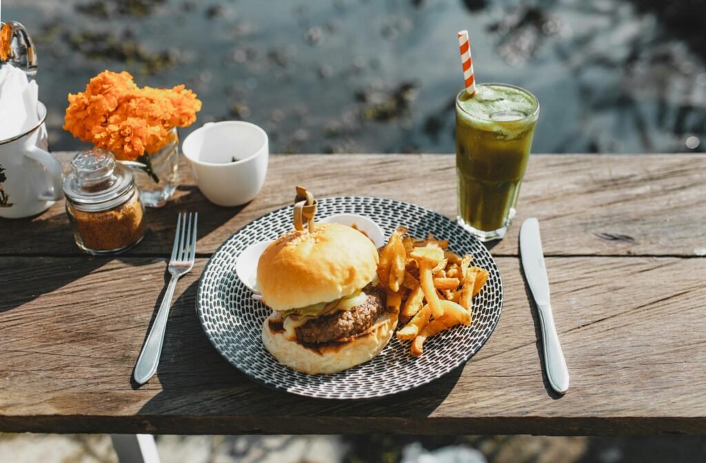 delicious burger with french fries and beverage on table in street cafe
