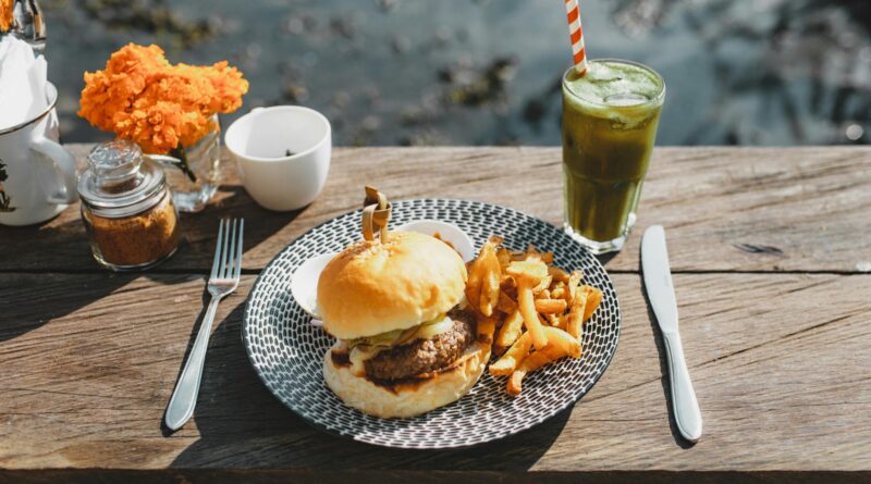 delicious burger with french fries and beverage on table in street cafe