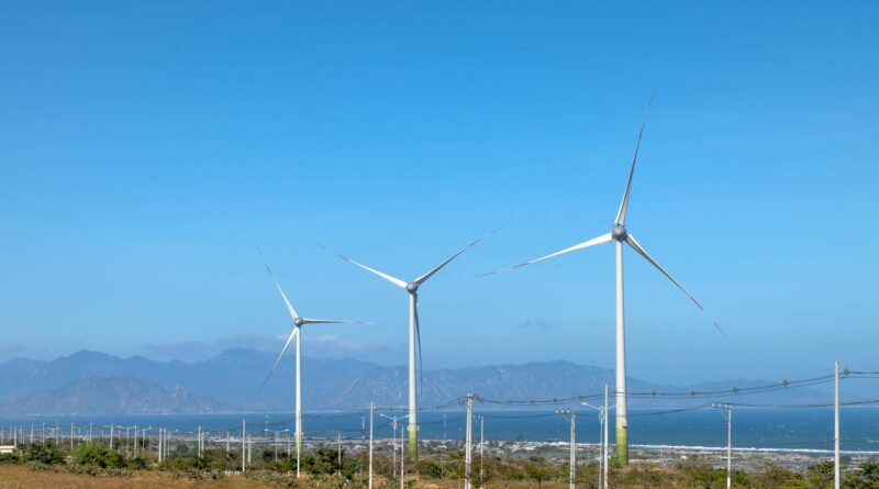 windmills against sea and ridges under blue sky