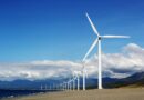 white wind turbines on gray sand near body of water