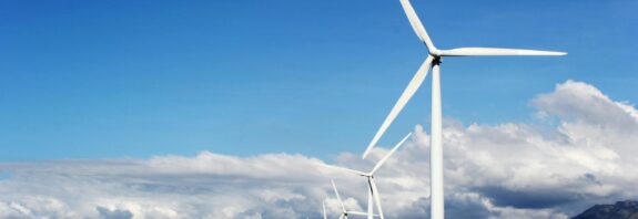 white wind turbines on gray sand near body of water