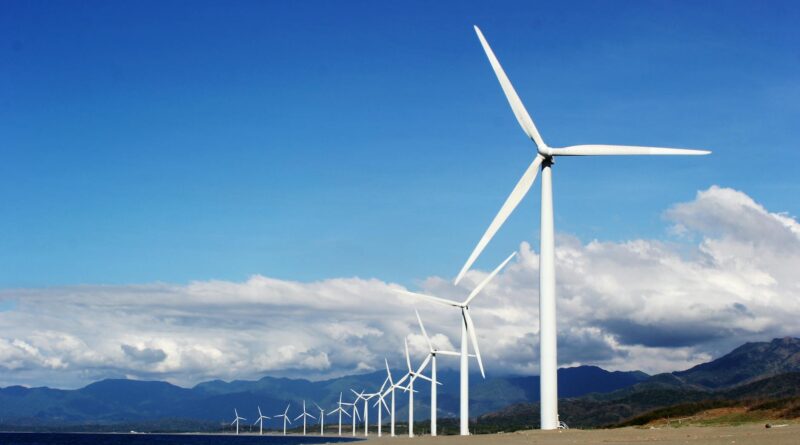 white wind turbines on gray sand near body of water