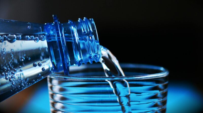 close up of bottle pouring water on glass