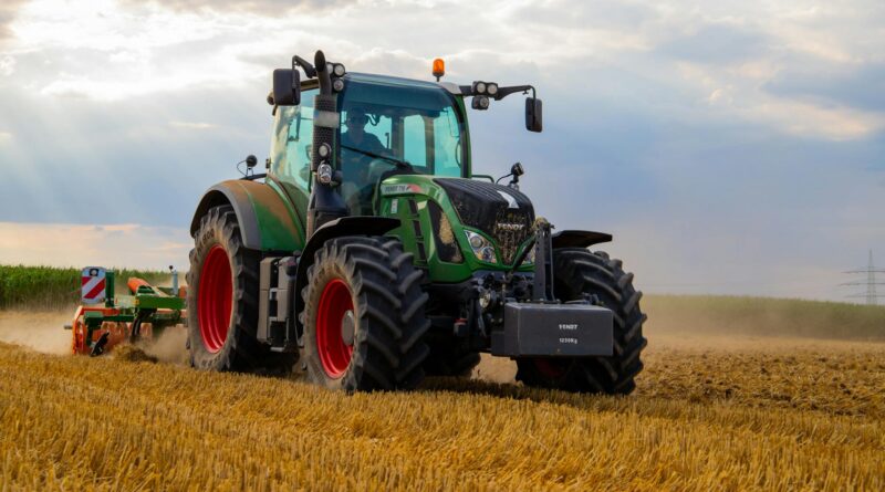 green tractor plowing the fields on focus photography