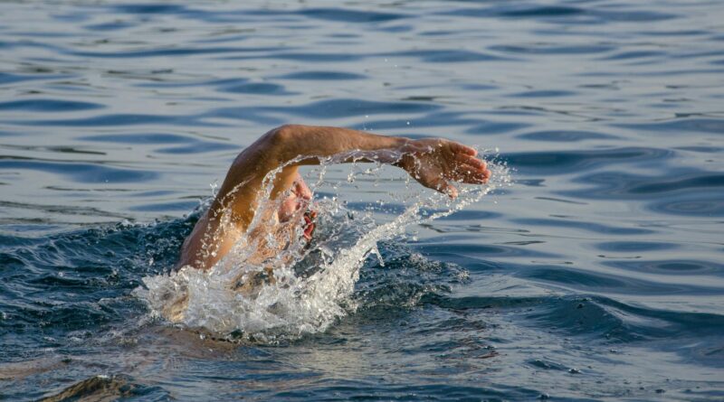 person swimming on body of water doing freestyle strokes