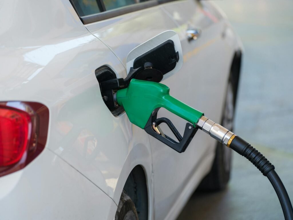 gas pump nozzle filling the white car