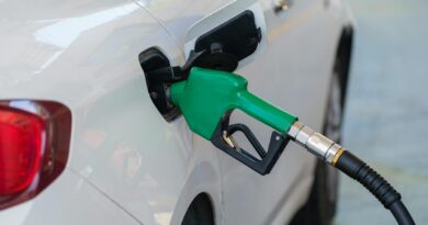 gas pump nozzle filling the white car