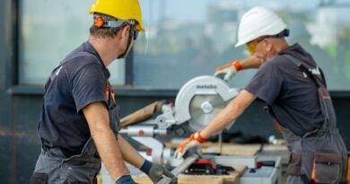 two workers cutting a metal beam with a saw
