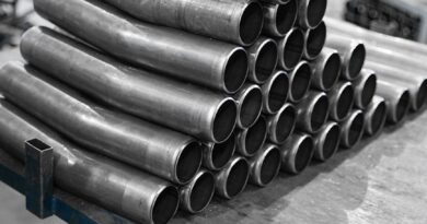 stack of slightly curved pipes on a table in a factory