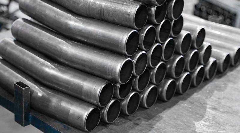 stack of slightly curved pipes on a table in a factory