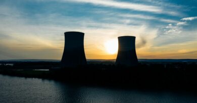 similar cooling towers near lake under bright sky at sunset