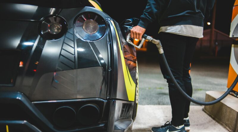 crop man refueling sports car in gas station