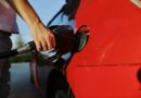 a person filling up a red car with gas