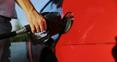 a person filling up a red car with gas