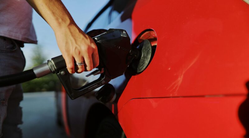 a person filling up a red car with gas